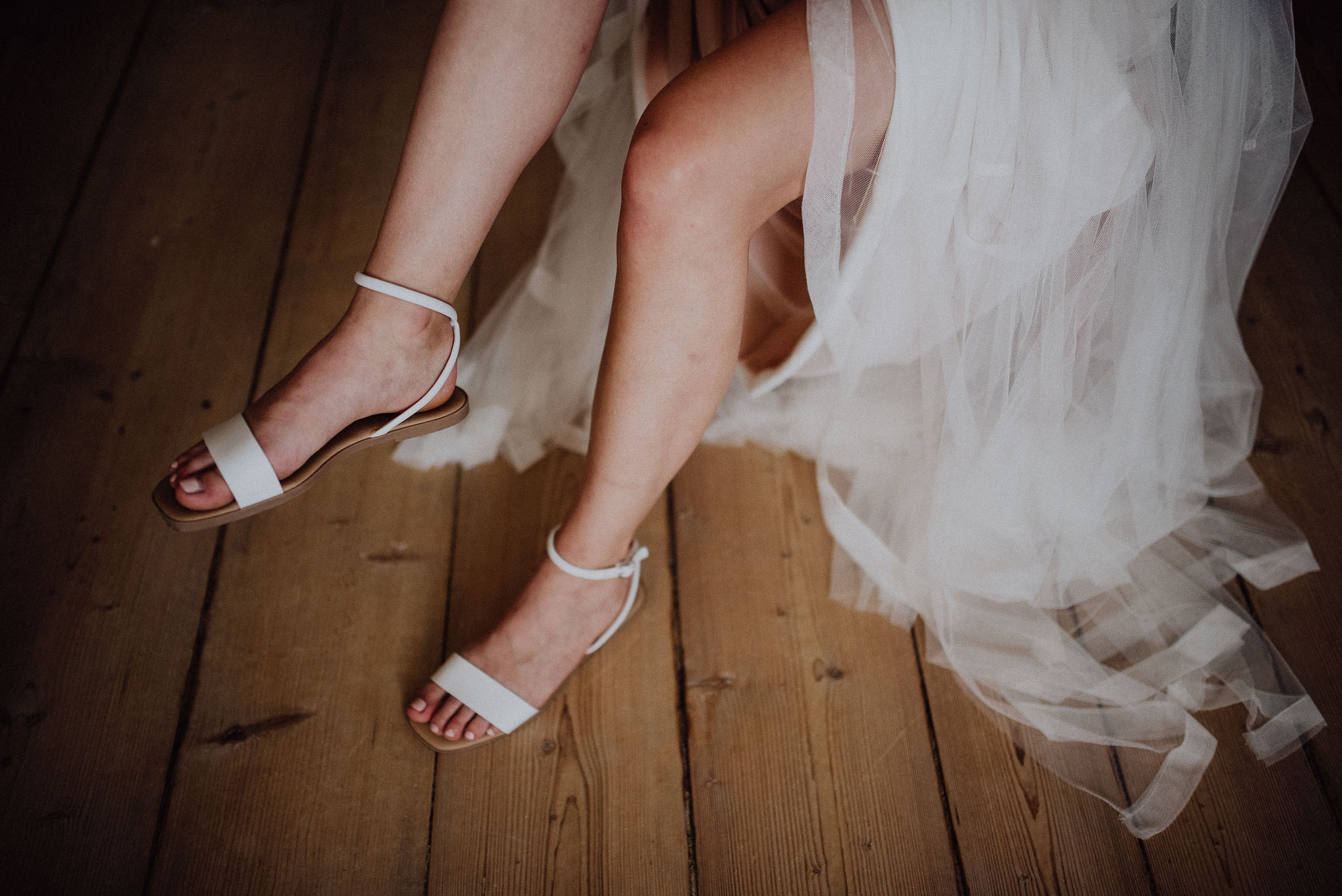 Nevěsta si v rustikální místnosti nazouvá svatební boty